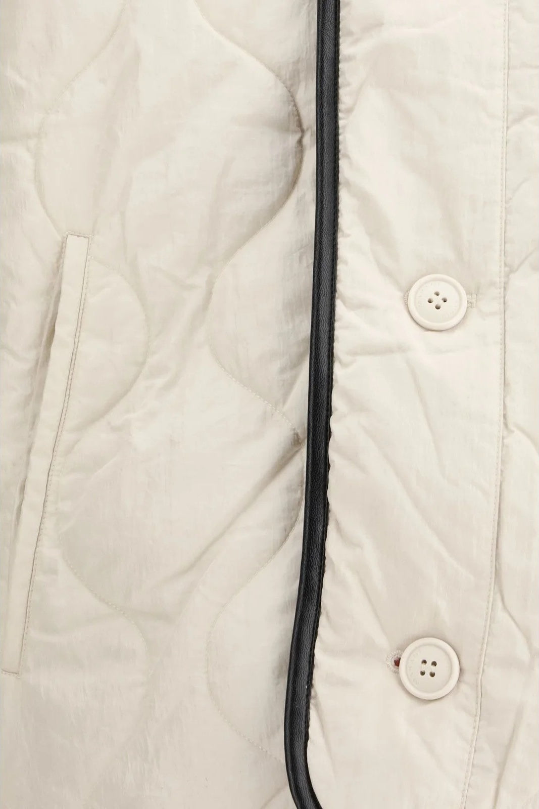 Close-up of a white quilted jacket with buttons and a zipper.