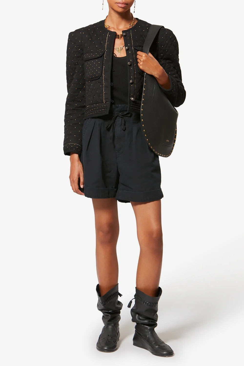 Person wearing a black textured jacket, black top, black shorts, and black boots on a white background