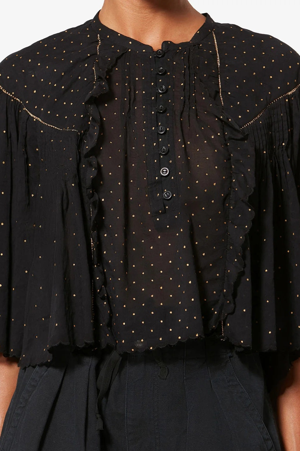 Black blouse with ruffled details and white polka dots on a white background