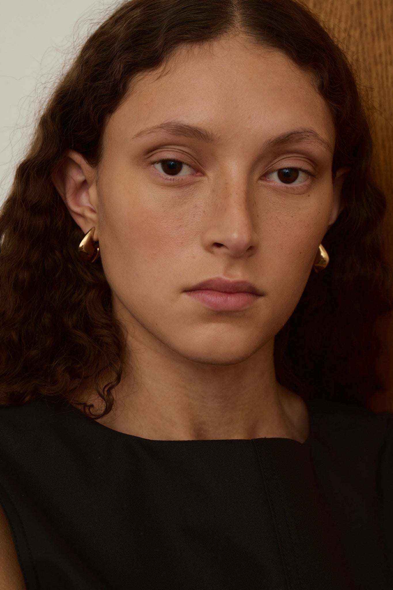 Close-up of a person with wavy hair wearing gold earrings.