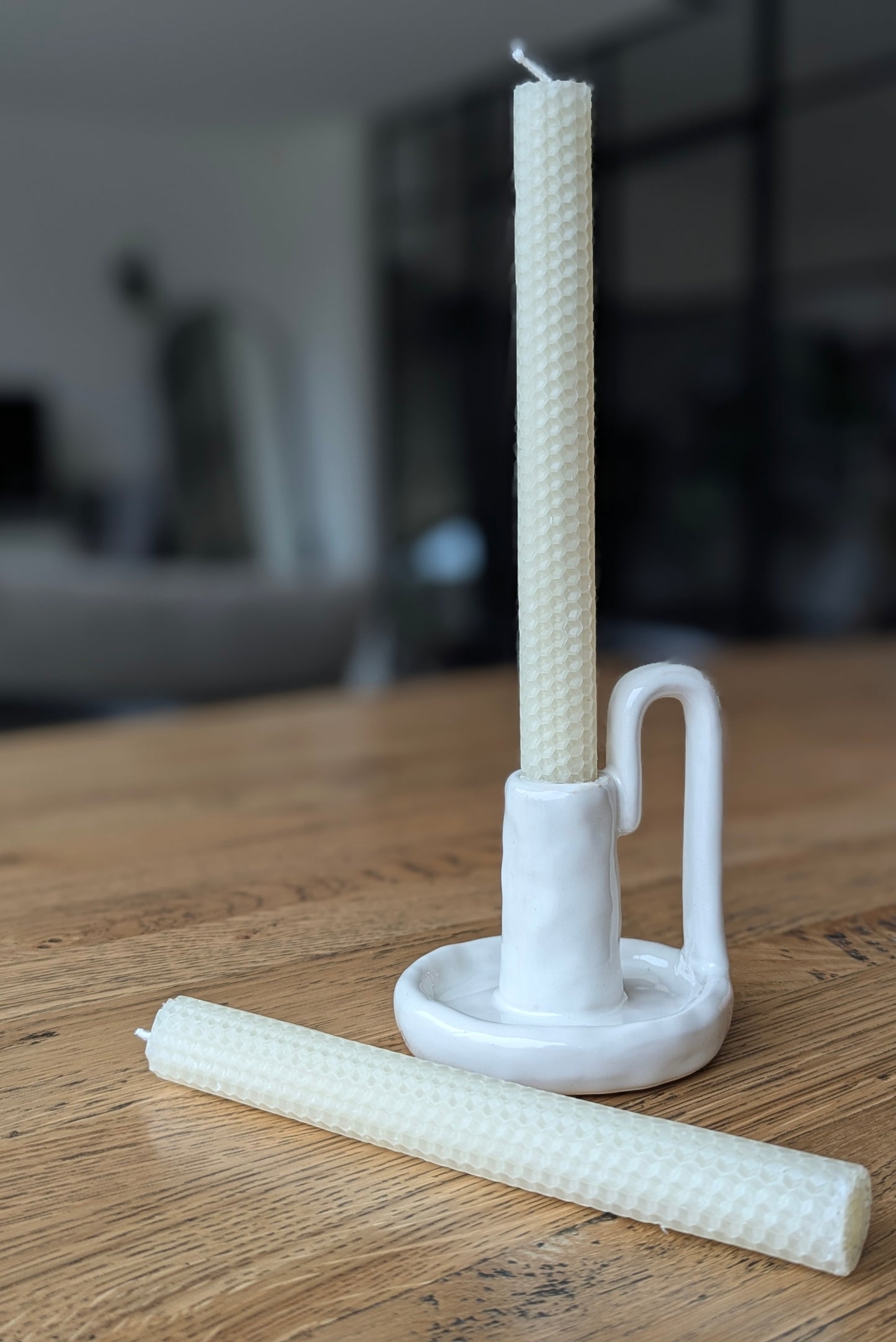 White candle holder with a candle on a wooden surface
