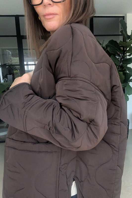 Woman wearing a brown puffer jacket indoors