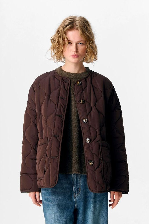 Woman wearing a brown quilted jacket on a white background