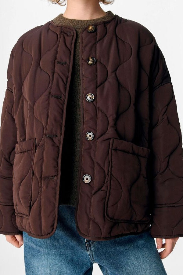 Brown quilted jacket worn by a person on a white background