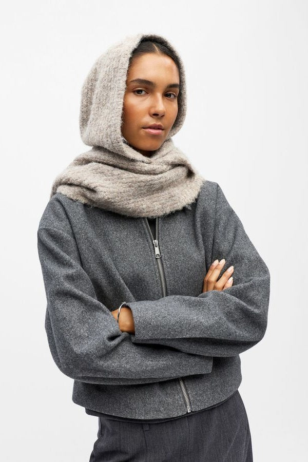 Person wearing a beige hooded scarf on a white background
