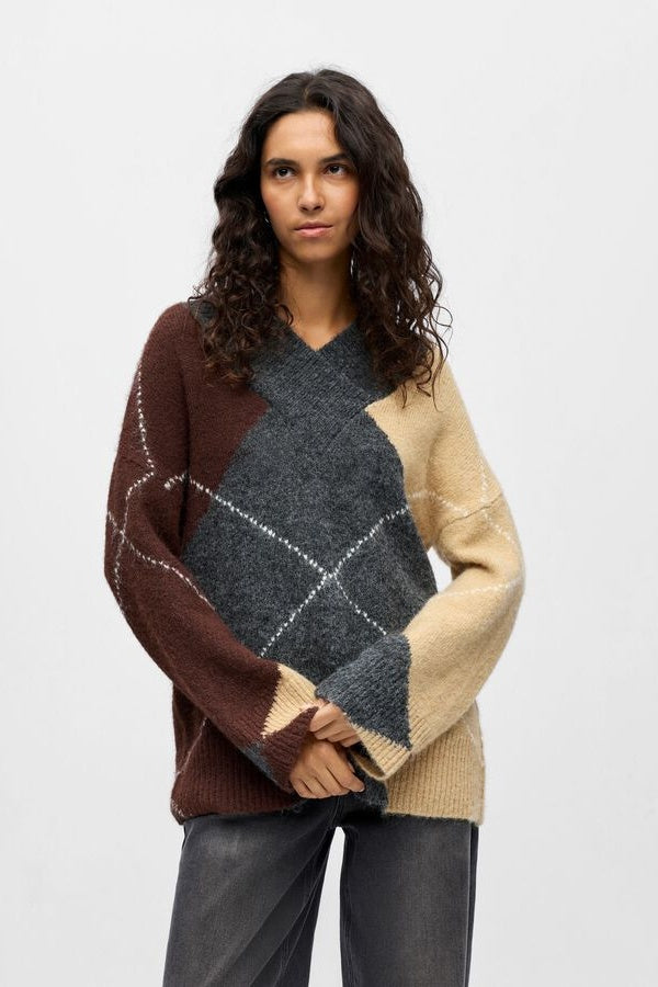 Woman wearing a multicolored sweater with a geometric pattern on a white background