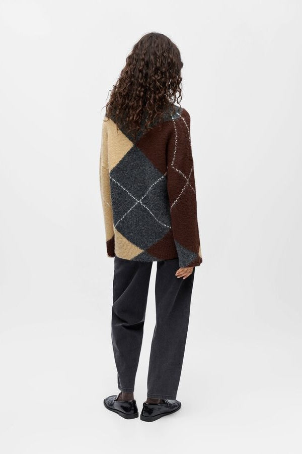 Person wearing a multicolored argyle sweater on a white background