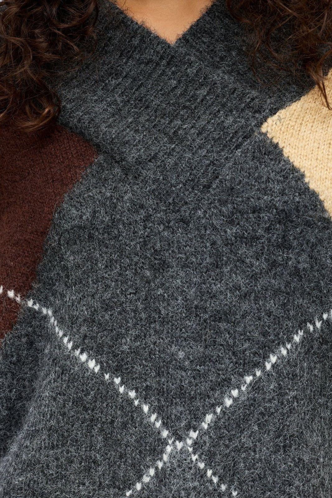 Close-up of a dark grey knitted sweater with white diamond pattern