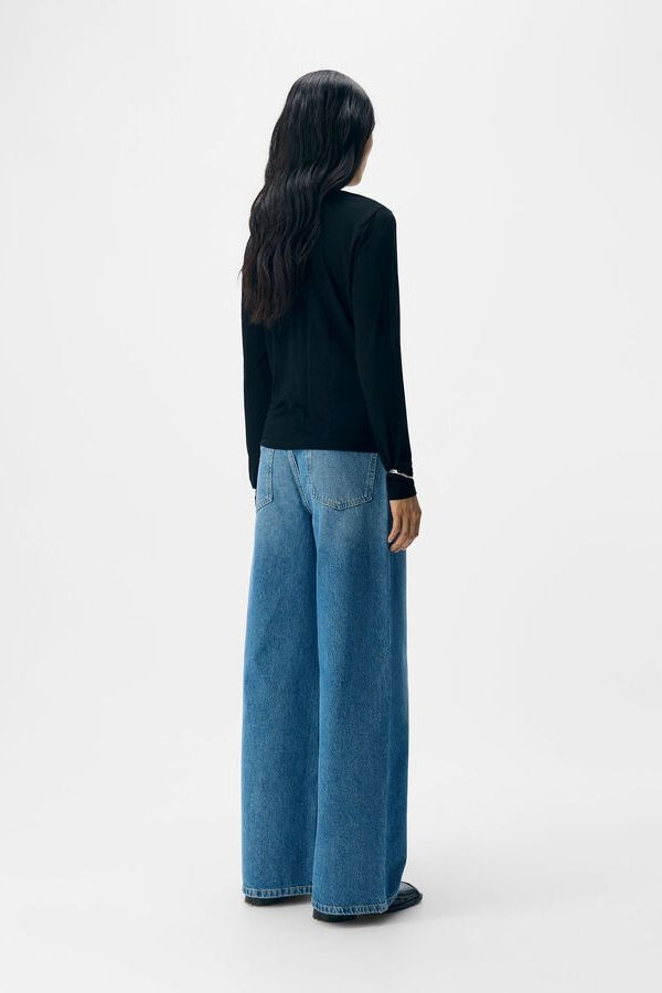 Person wearing a black top and blue jeans on a white background