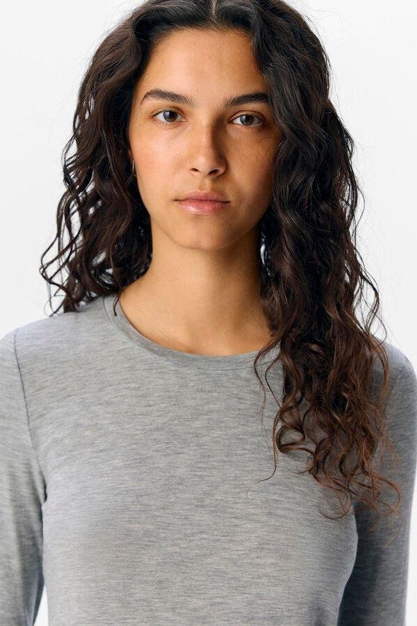Woman wearing a grey long-sleeve shirt against a white background