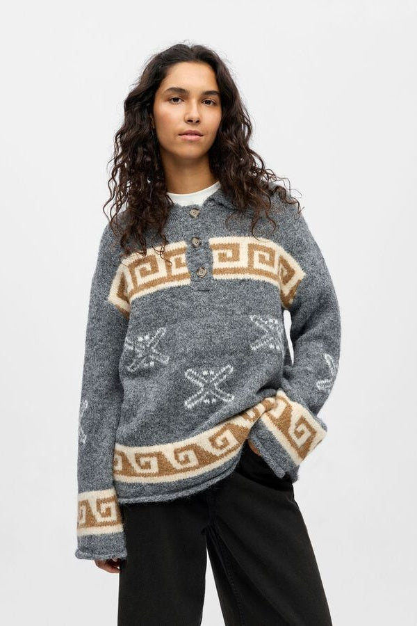 Person wearing a patterned sweater with a plain background
