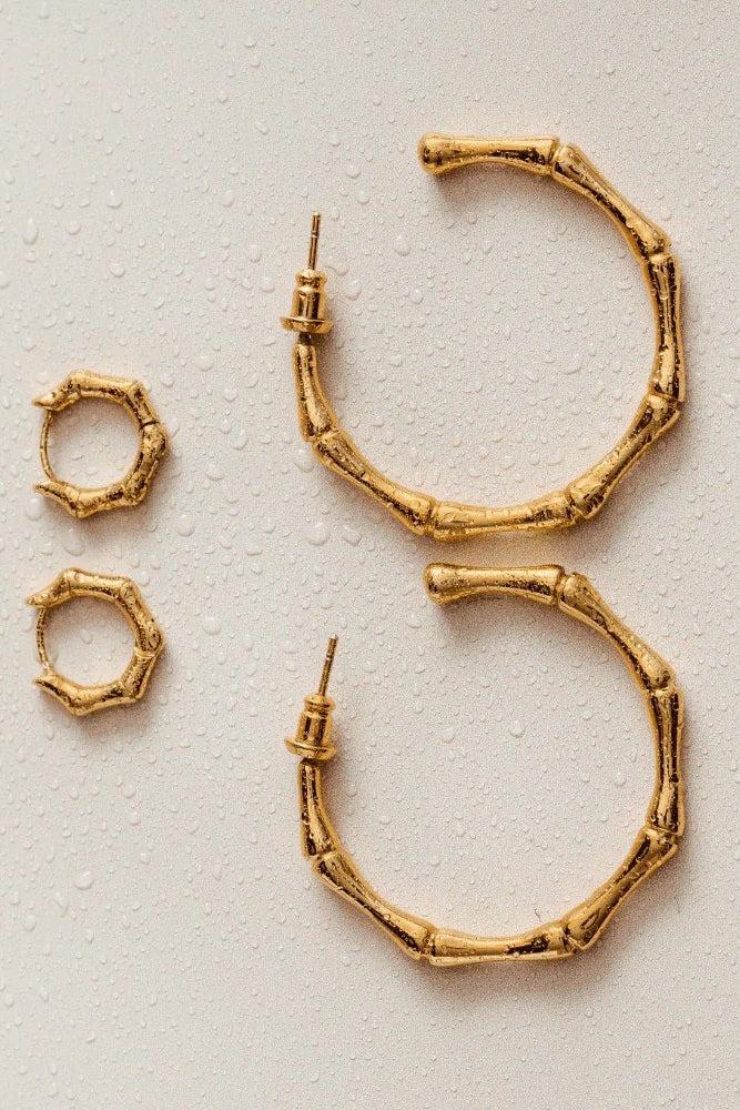 Gold hoop earrings on a textured beige background