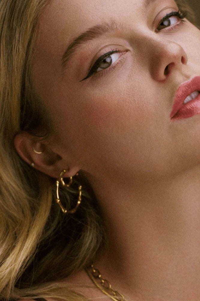 Close-up of a woman wearing gold hoop earrings with a soft focus on her face.