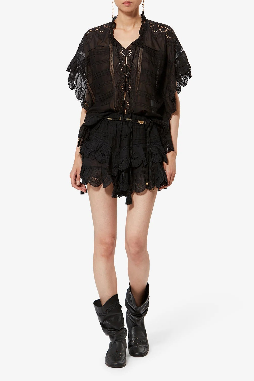 Person wearing a black lace outfit with boots on a white background
