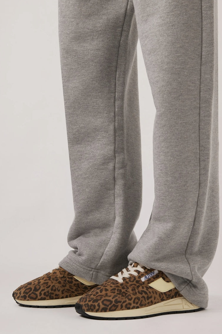 Person wearing gray sweatpants and leopard print sneakers on a plain background