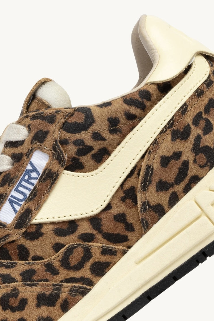 colse up detail of autry logo on leopard print trainer with cream leather trims on white background.