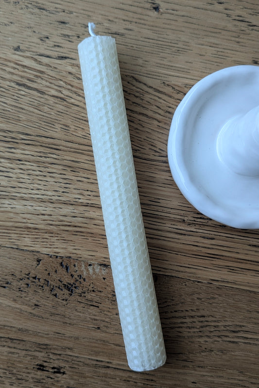 Textured white candle on a wooden surface with a white lid.