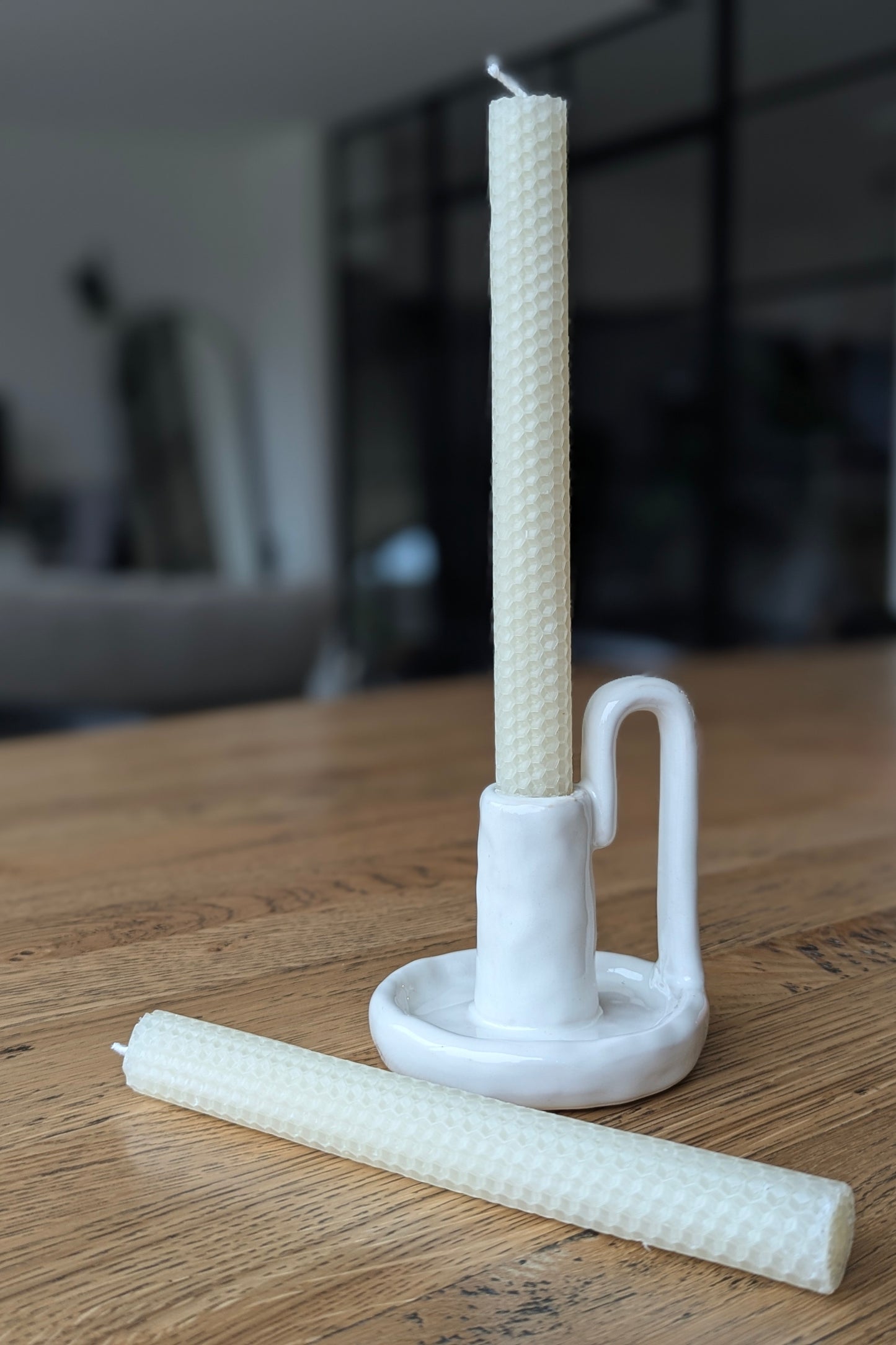 White candle holder with two candles on a wooden surface