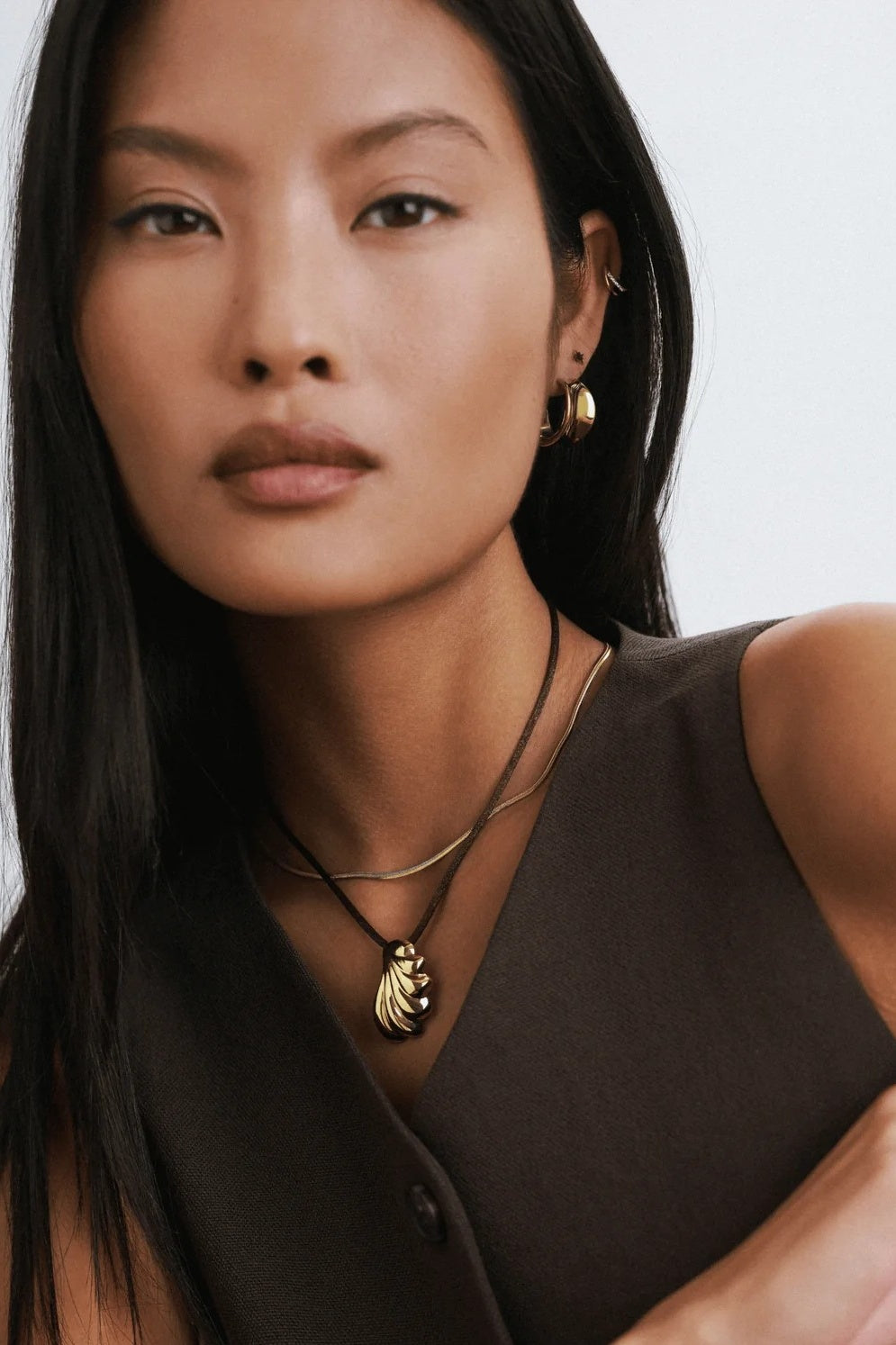 Woman wearing a necklace with a pendant against a white background