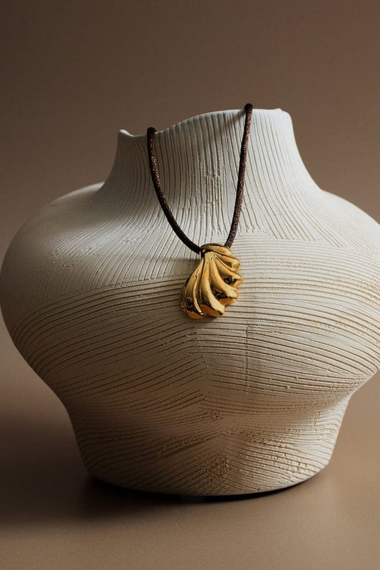 Necklace with a pendant on a textured vase against a brown background
