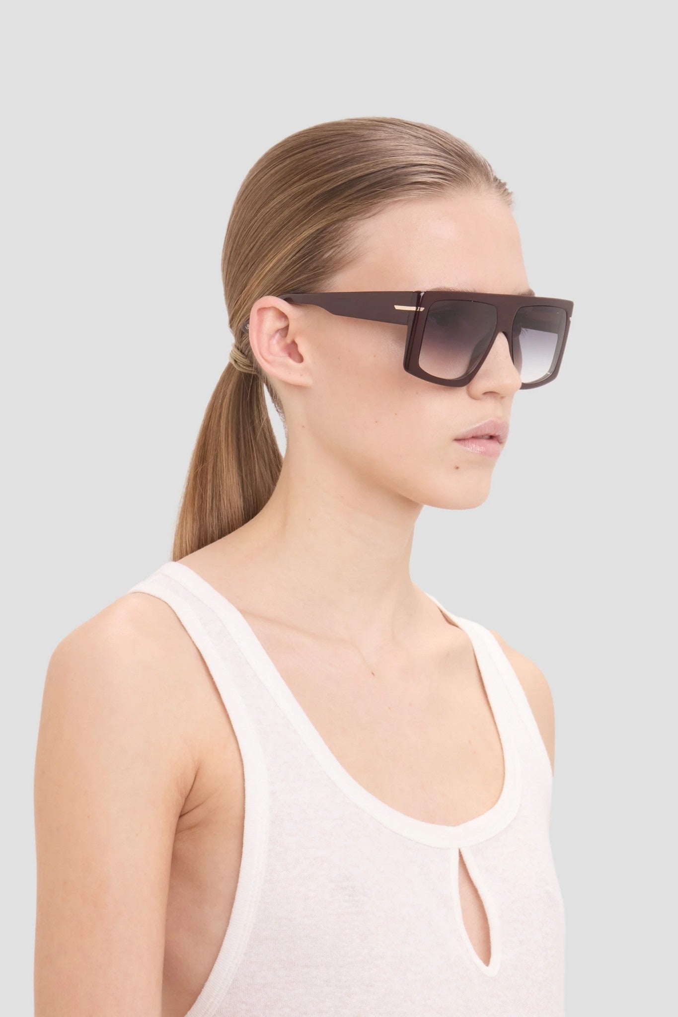 Woman wearing dark sunglasses against a light gray background