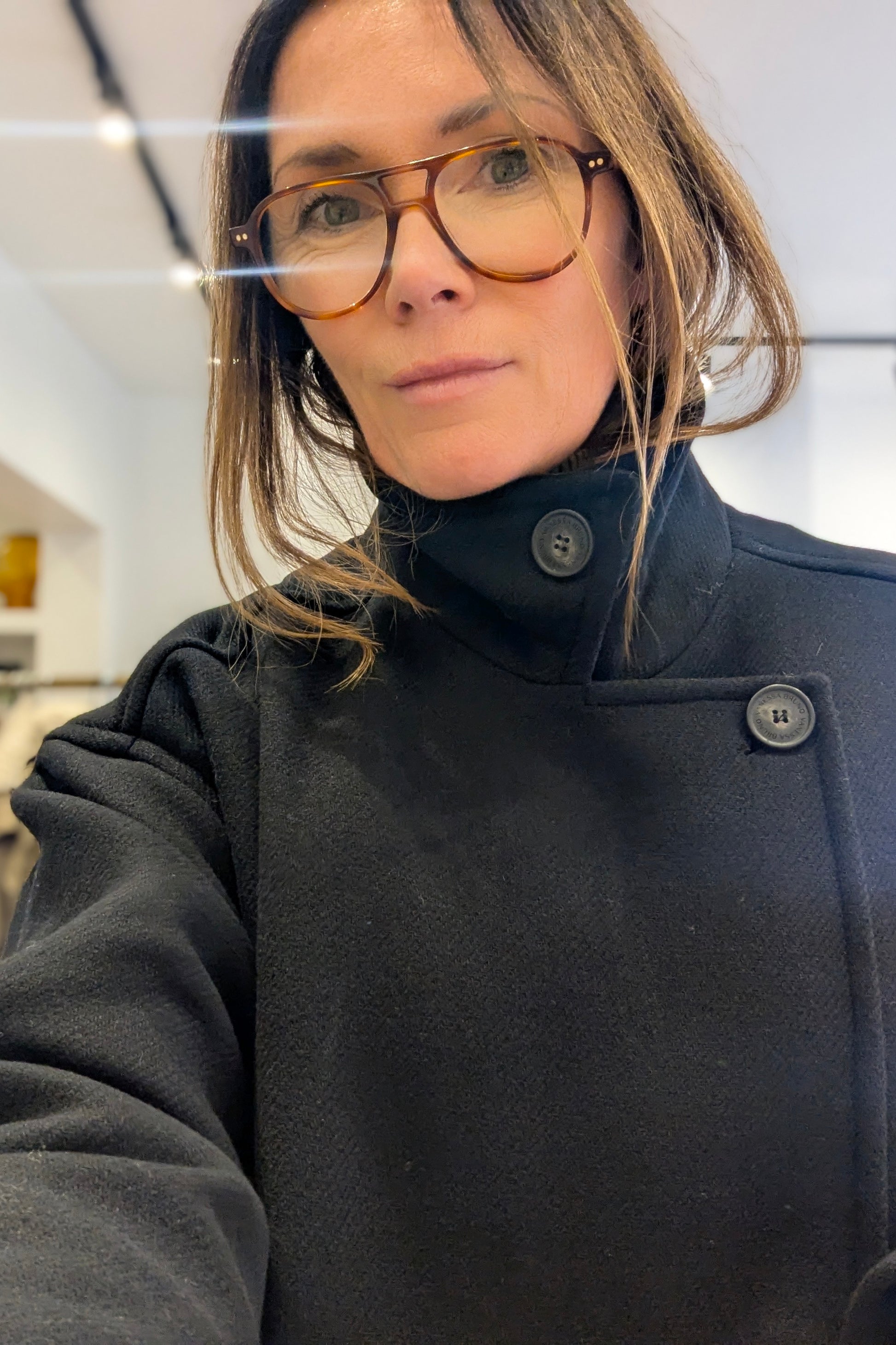 Person wearing a dark coat with a blurred indoor background