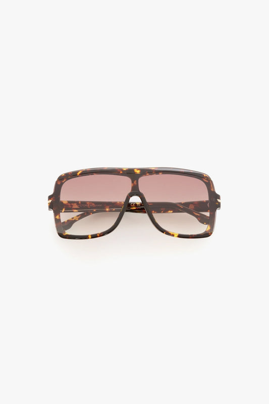 Sunglasses with tortoiseshell frame and pink lenses on a white background