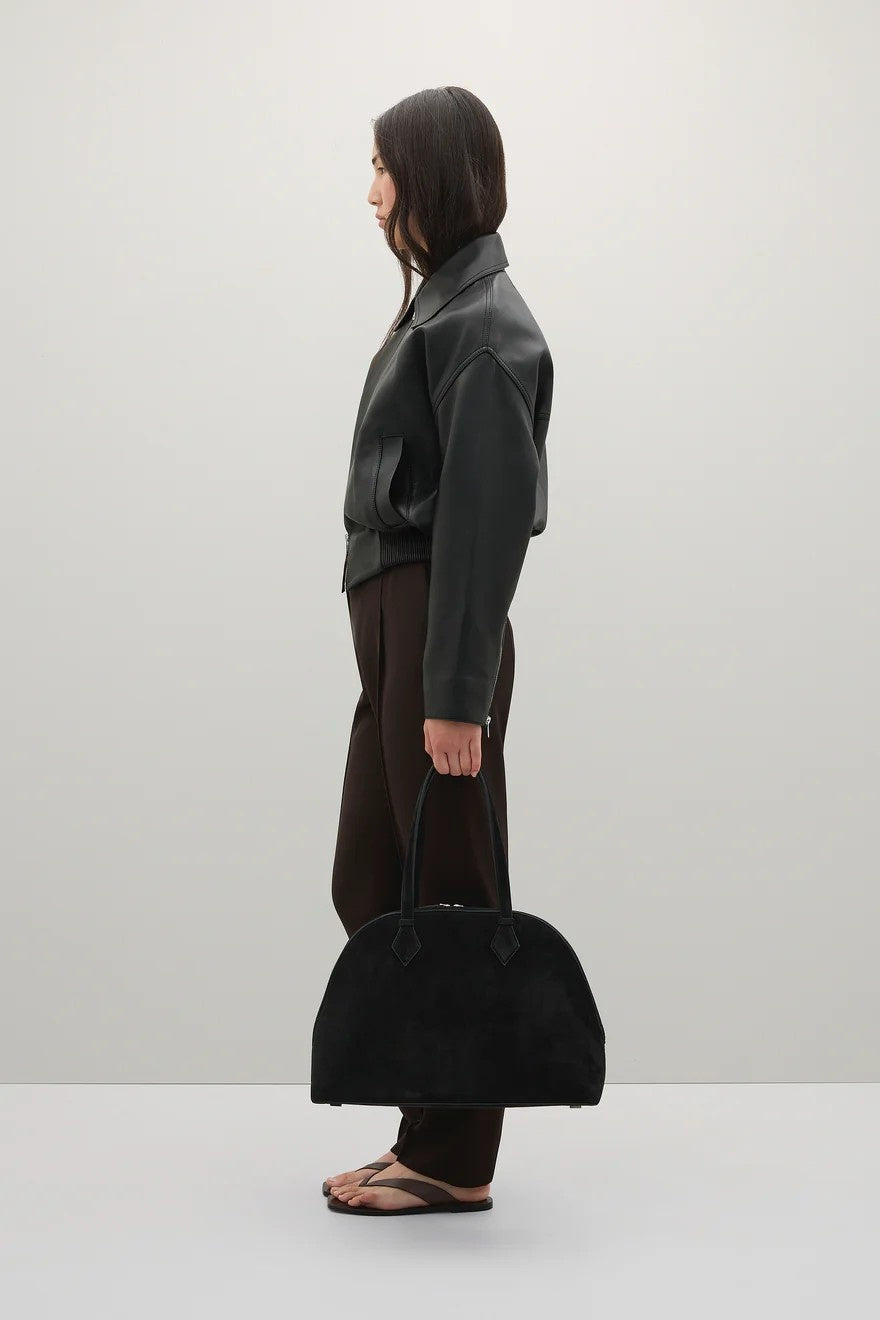 Person holding a black handbag against a plain background
