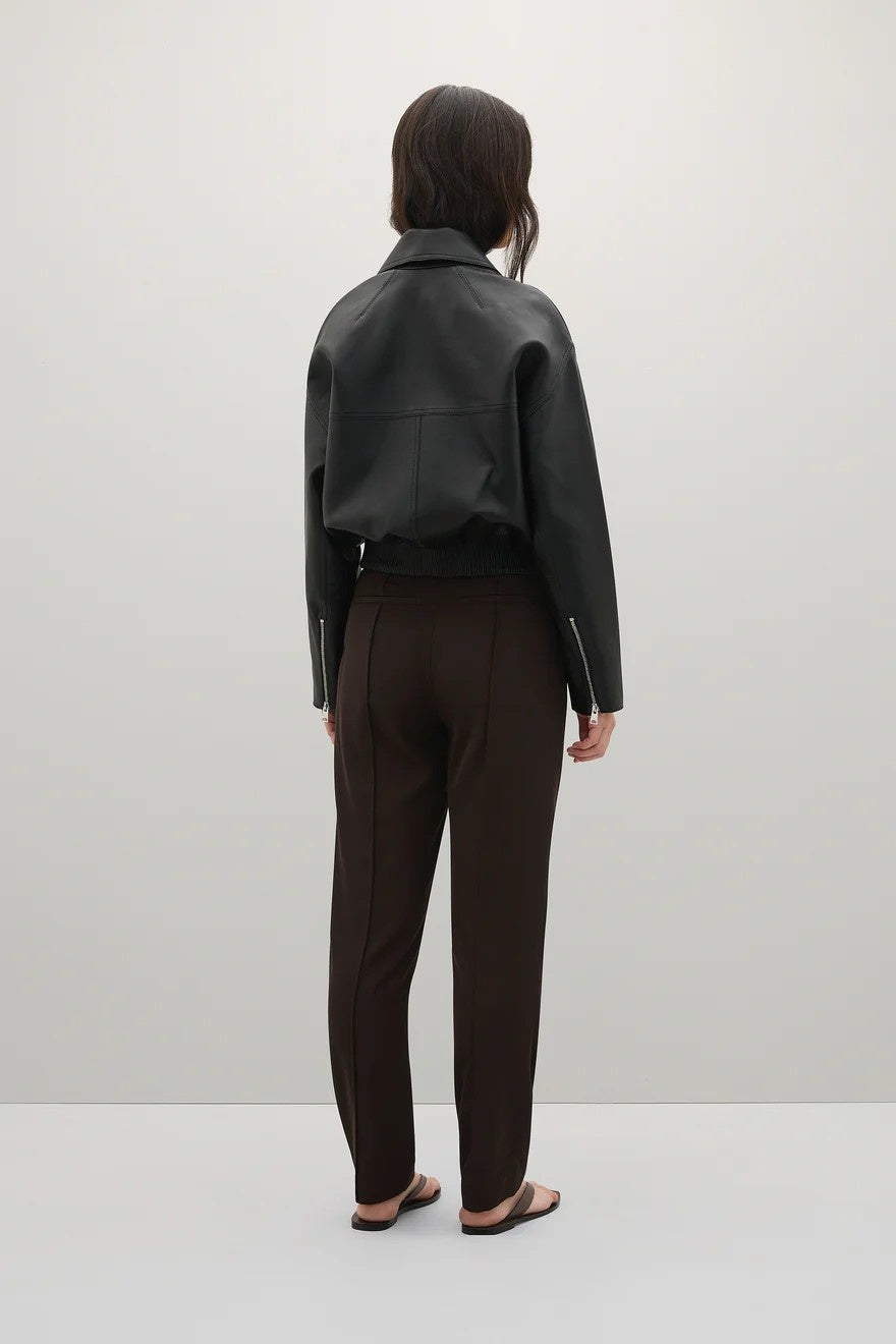 Person wearing a black  jacket and brown pants on a white background