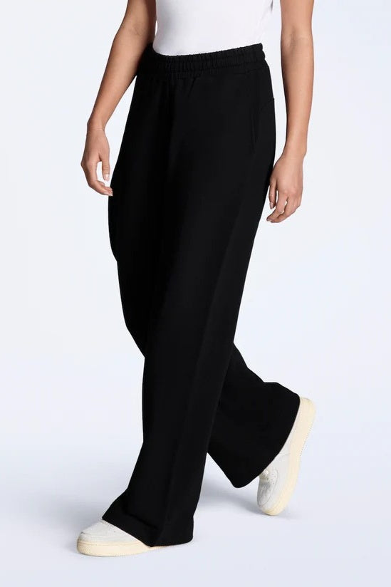 Person wearing black wide-leg pants on a white background