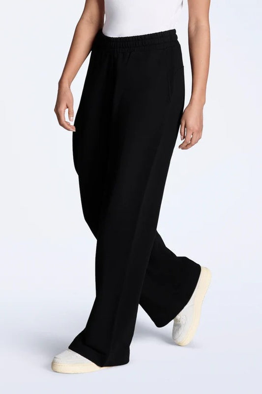 Person wearing black wide-leg pants on a white background