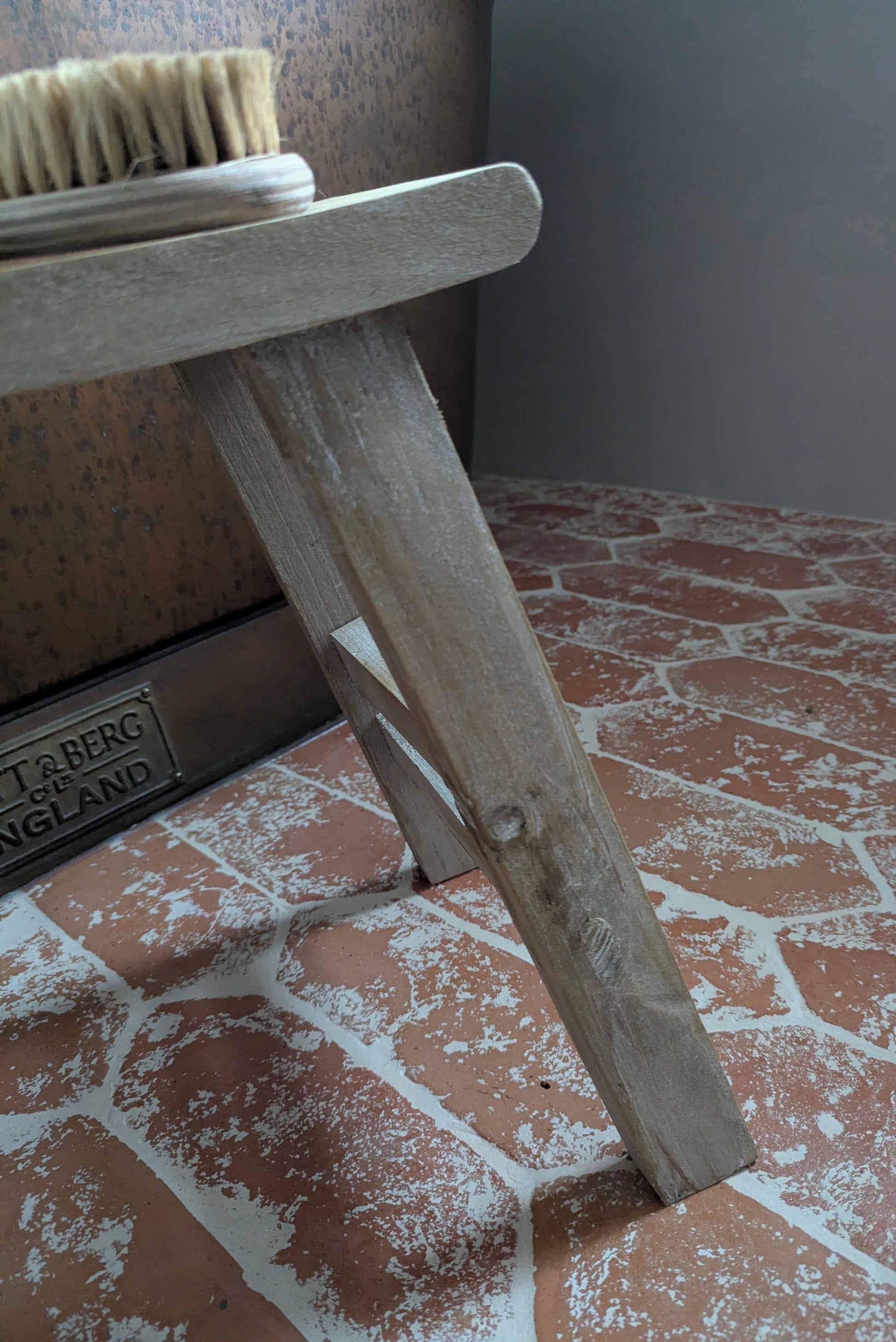 Wooden brush stand with a brush on a tiled floor