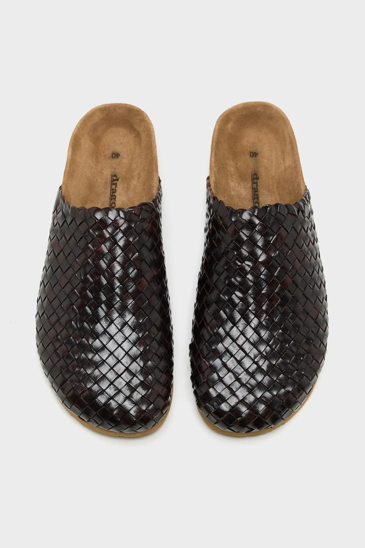 Pair of brown woven clogs on a light gray background