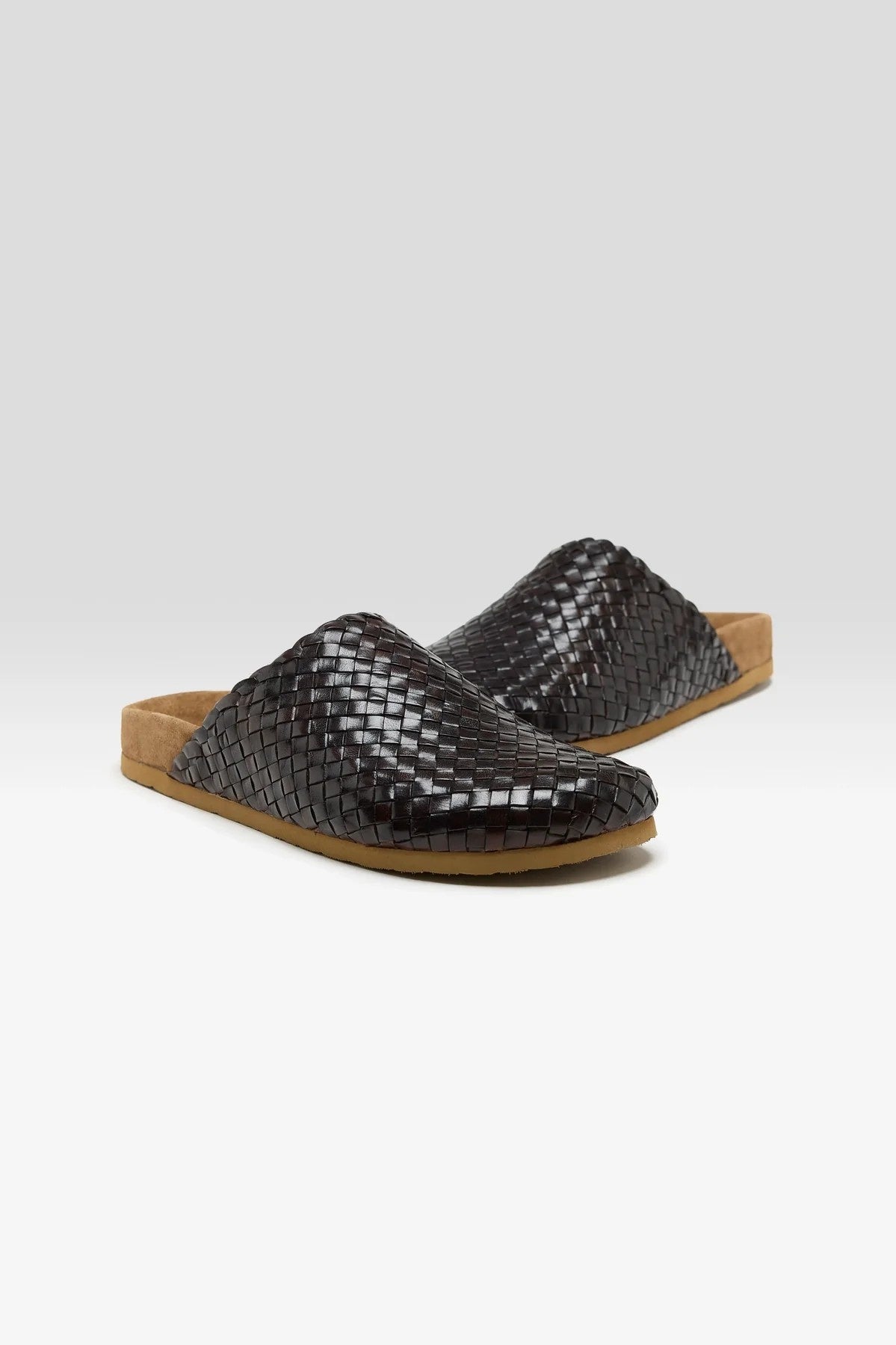 Pair of woven brown mules on a light gray background