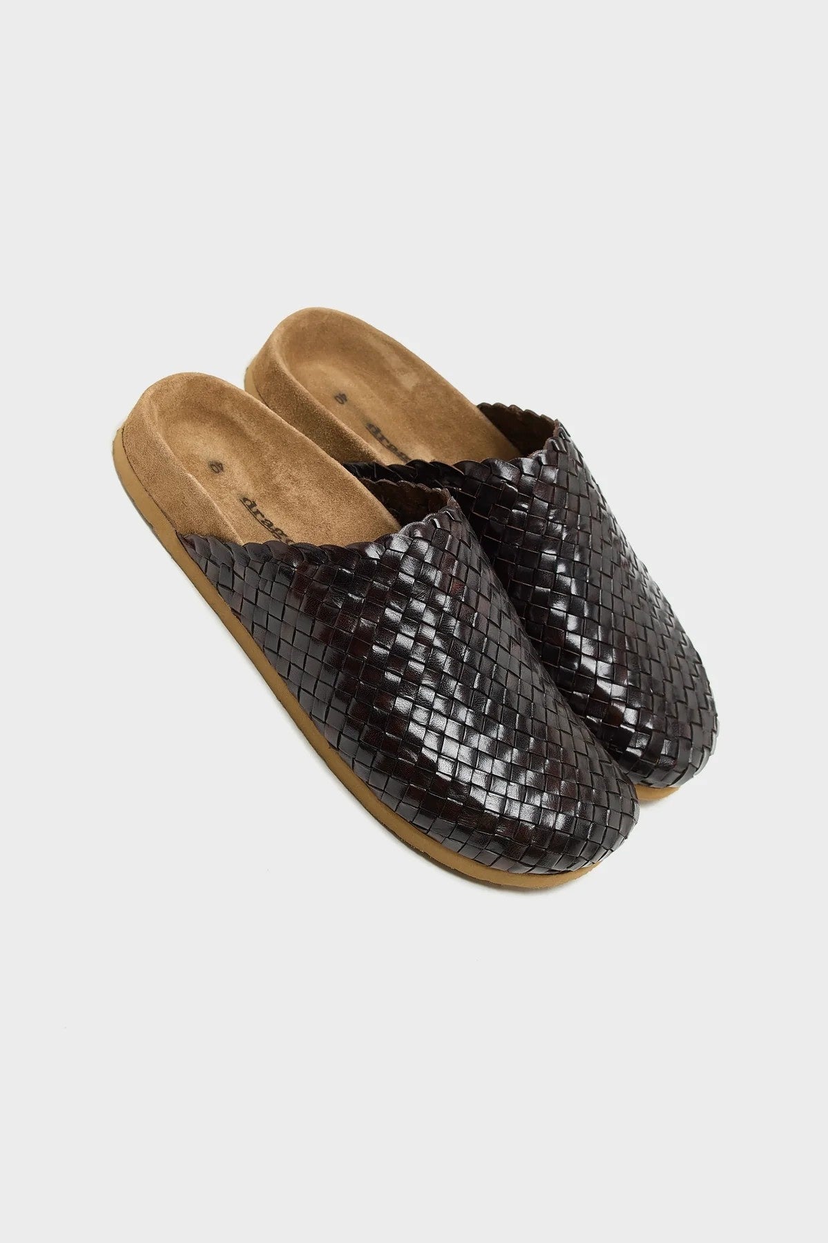 Pair of brown woven slippers on a light gray background